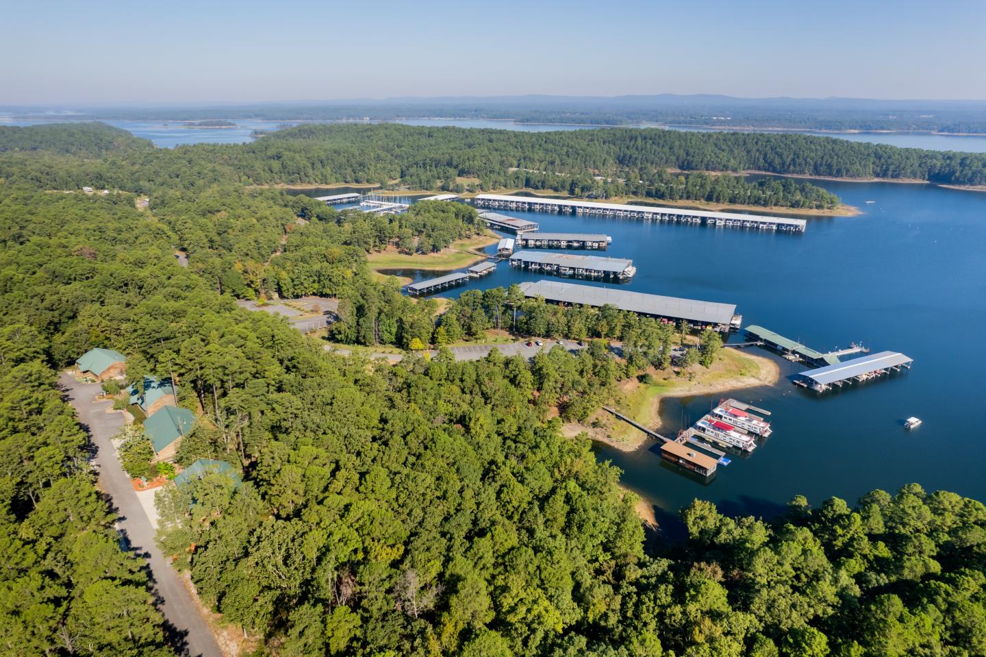 Aerial view of a marina surrounded by a lush green forest and calm blue water.