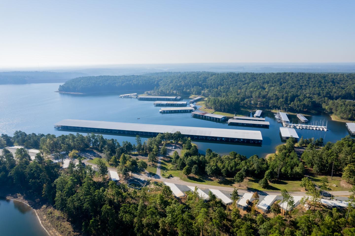 Aerial view of a marina with docks, surrounded by forest and water.