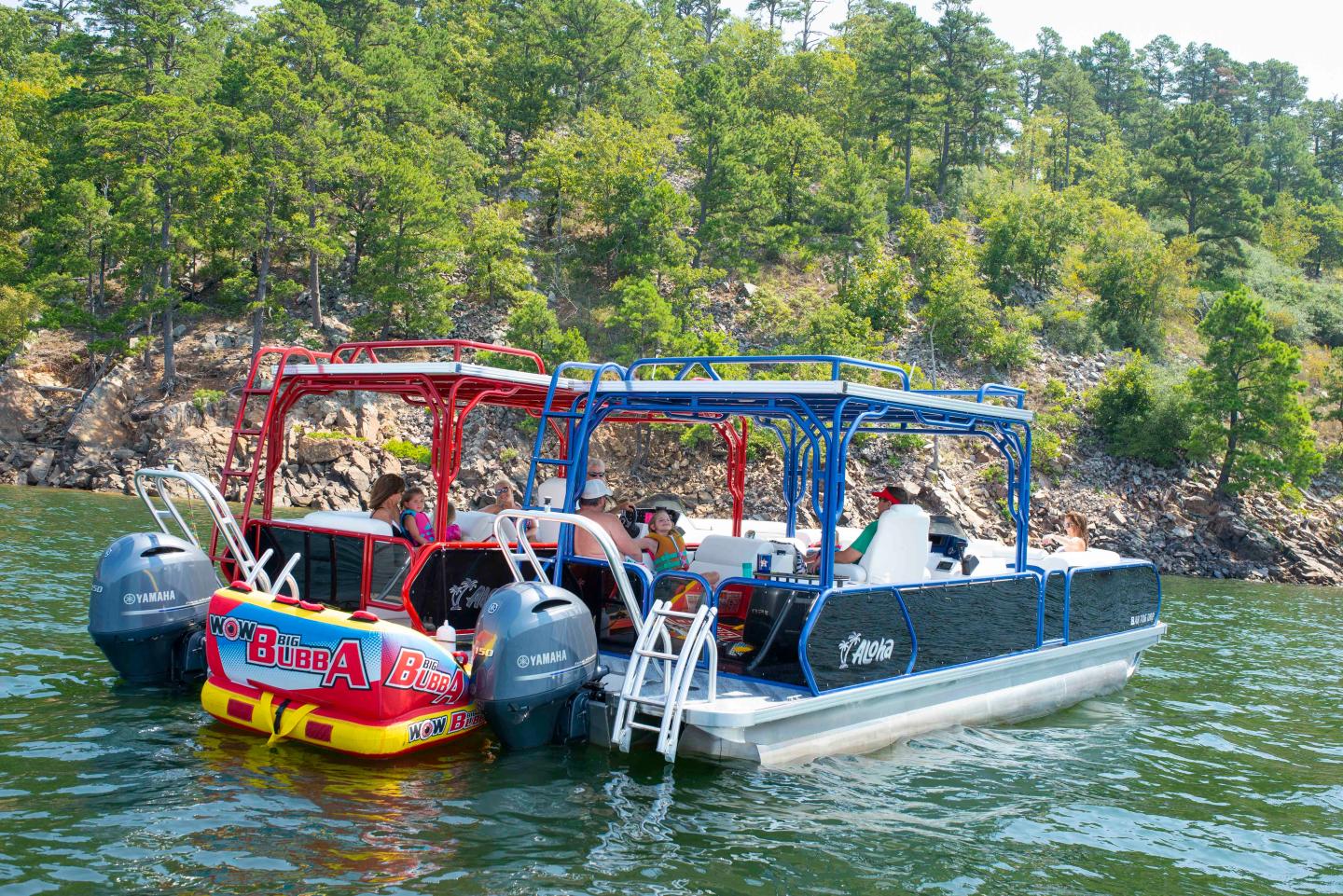 Two pontoons on lake, people relaxing, forested shore in background.
