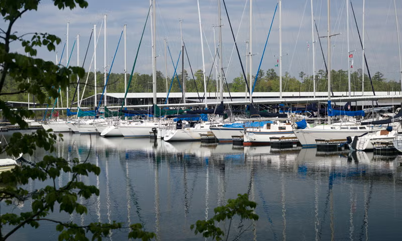Docked sailboats on a calm lake under a cloudy sky.