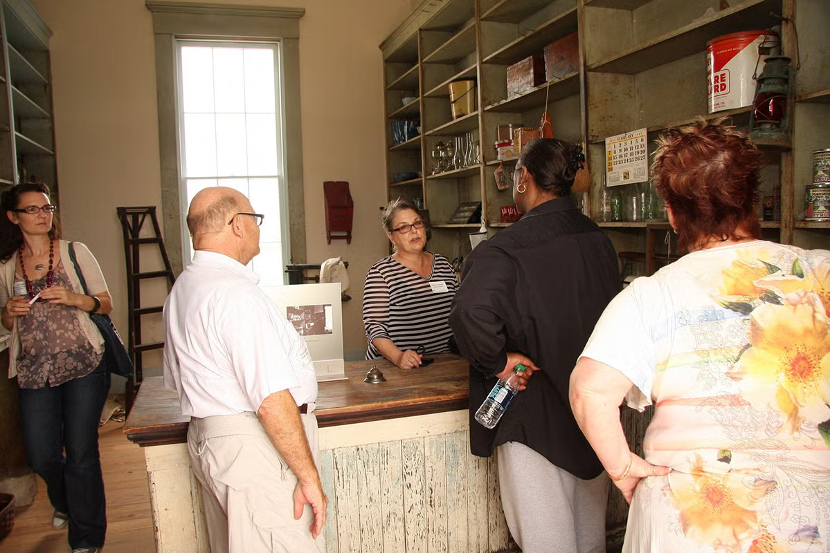 Group gathered around a counter in a historical apothecary setting.