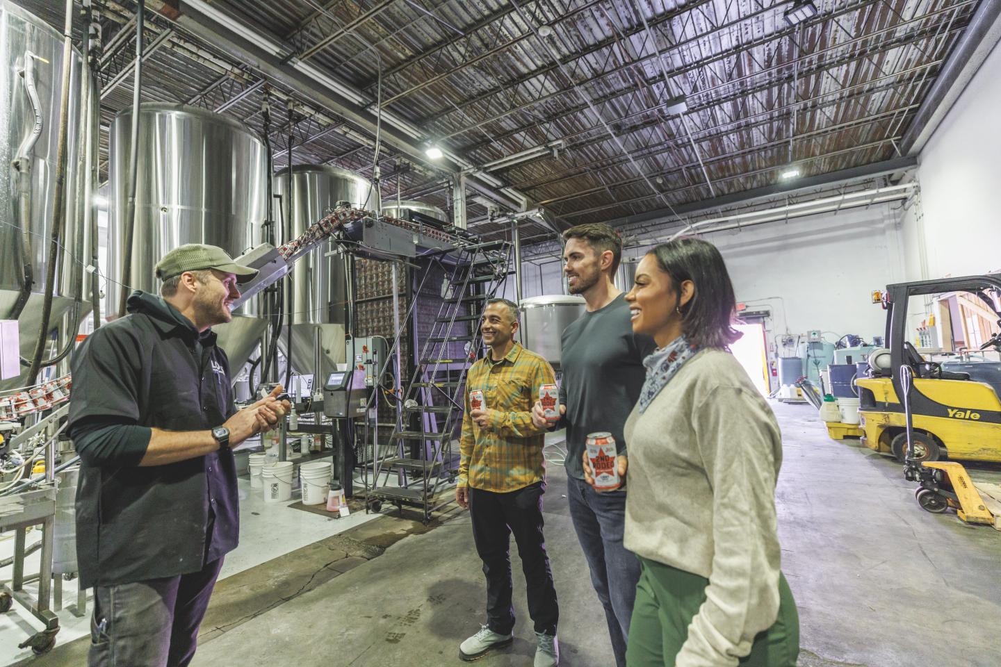Tour guide explains Lost Forty brewery equipment to engaged group.