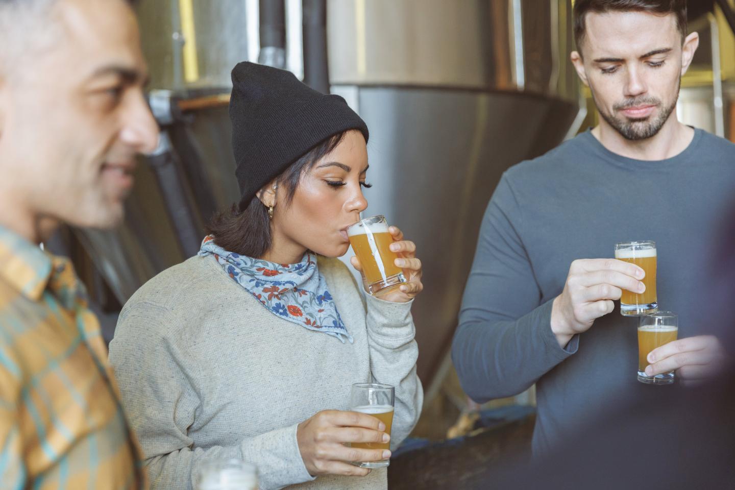 People tasting beer at Lost Forty, holding glass mugs.