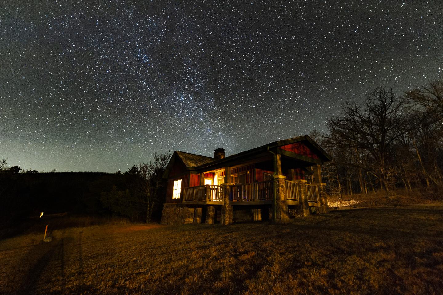 A Mount Magazine cabin under a starry night sky with trees surrounding.
