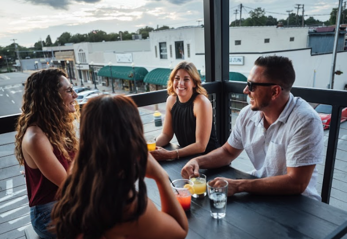 Friends chatting at an outdoor café table, drinks in hand.