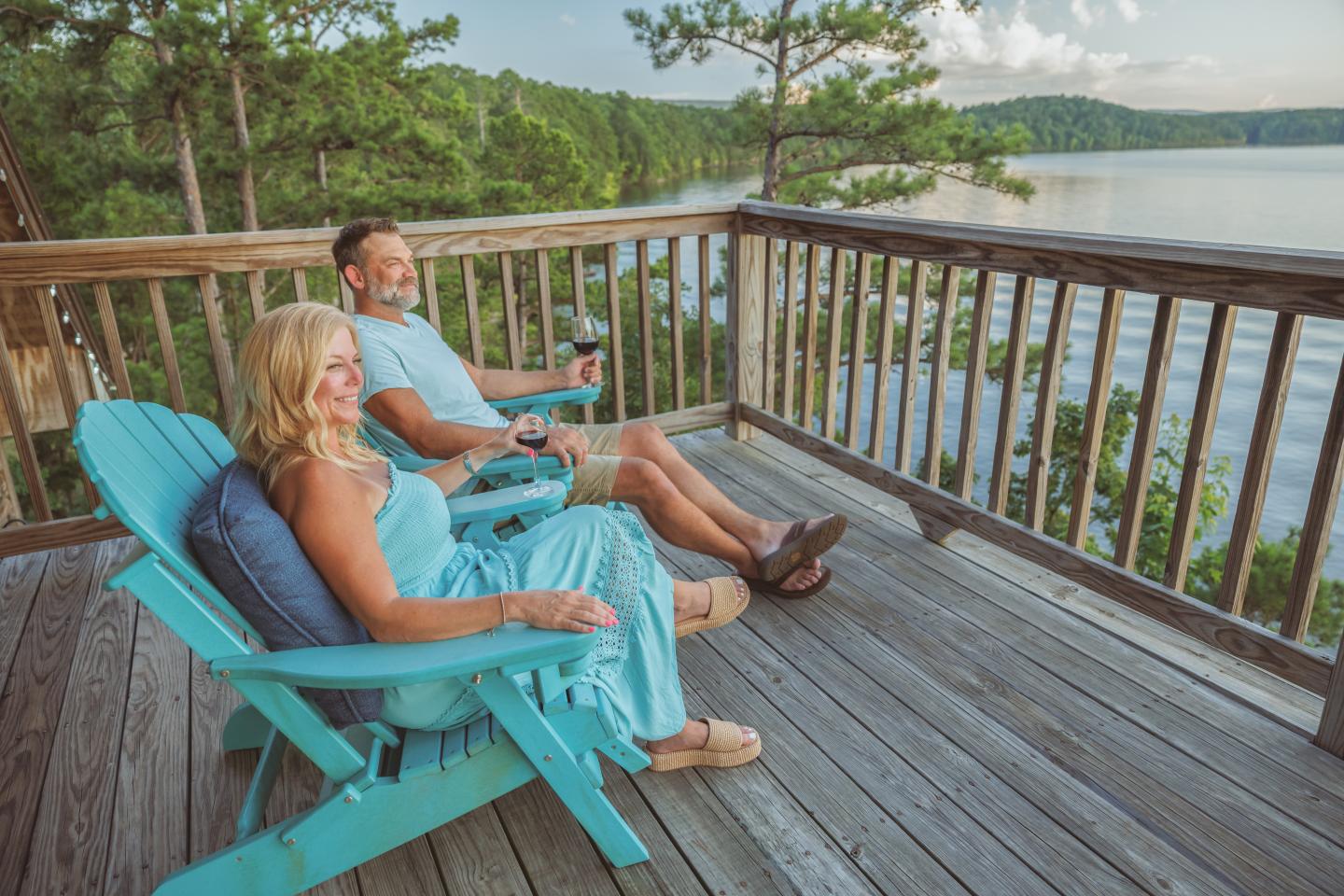 Couple relaxing on deck overlooking a serene lake and forest.