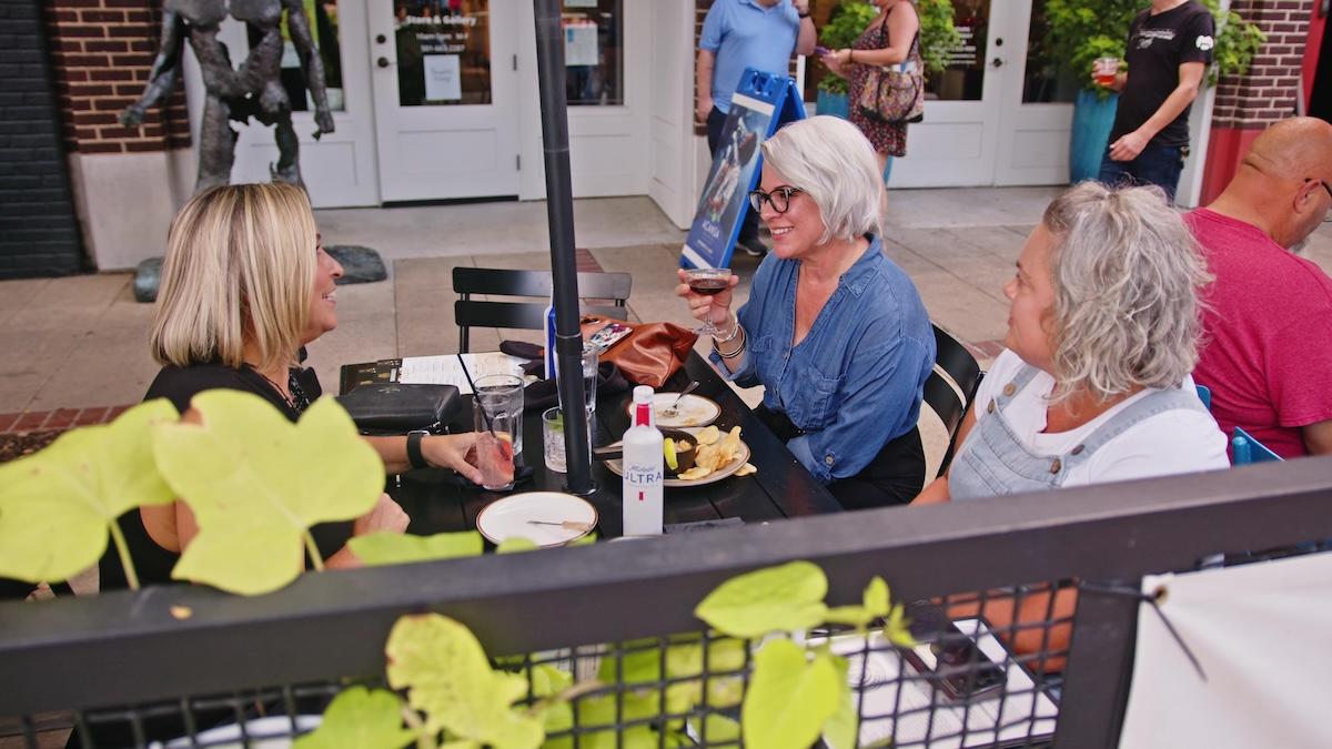 Women dining outdoors, engaged in conversation.