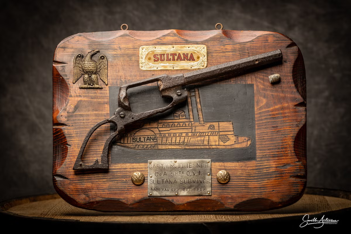 Antique gun mounted on a wood plaque with ship engraving and metal plates.
