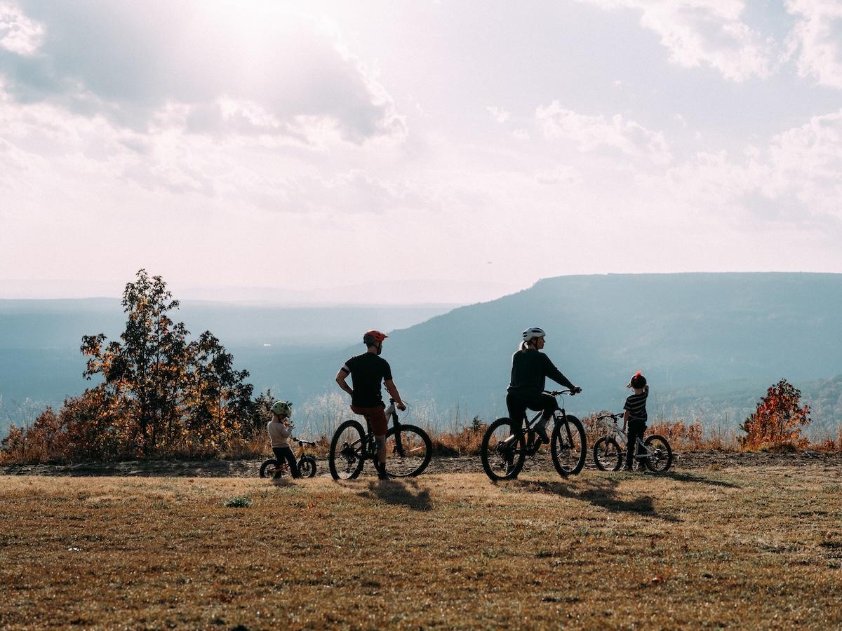 Cyclists on a hill under a bright sky.