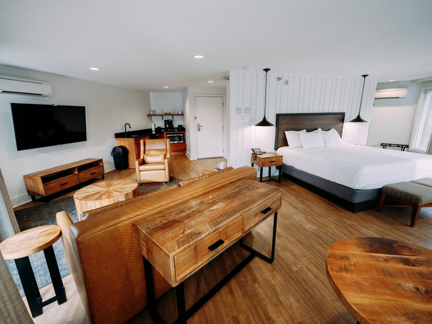 Spacious hotel room with a bed, sofa, and wooden furniture.
