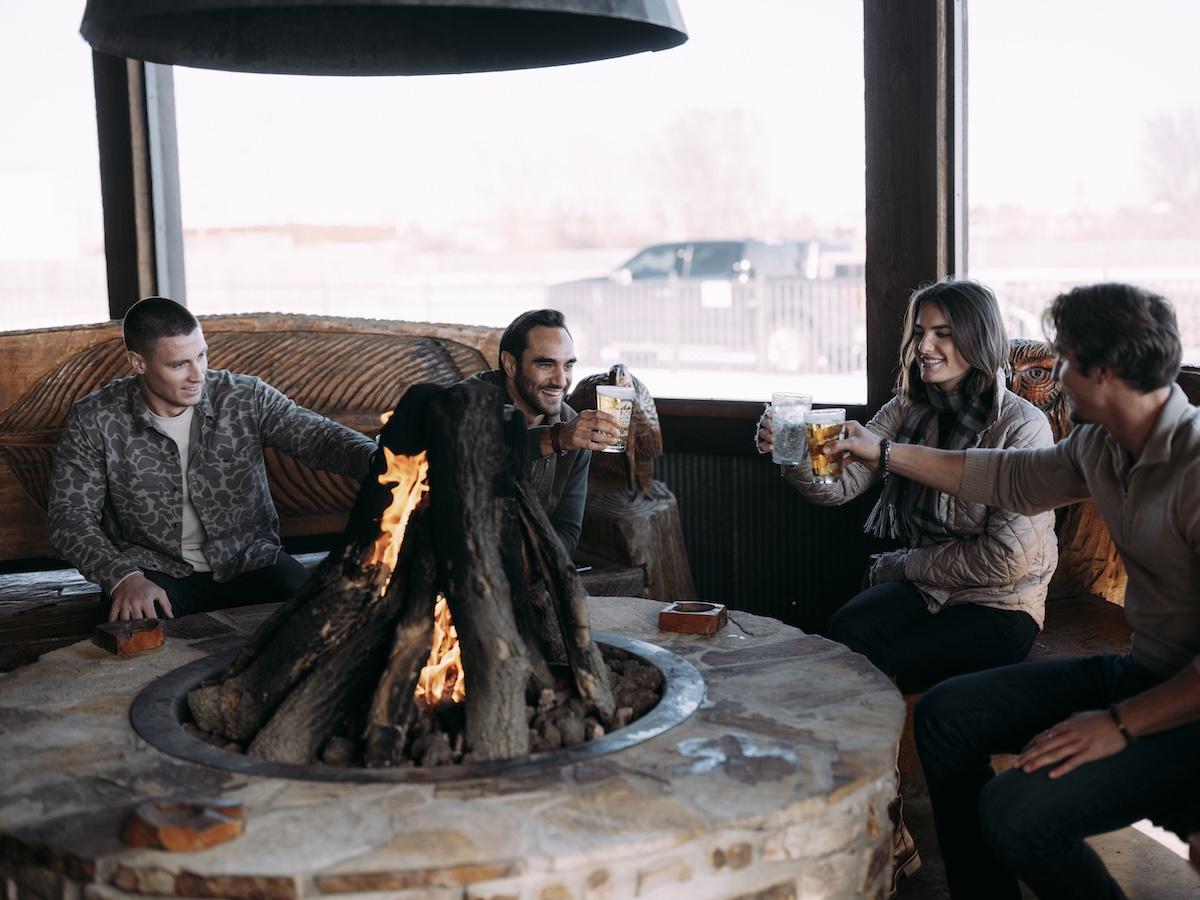 Friends toasting drinks around a cozy indoor fire.