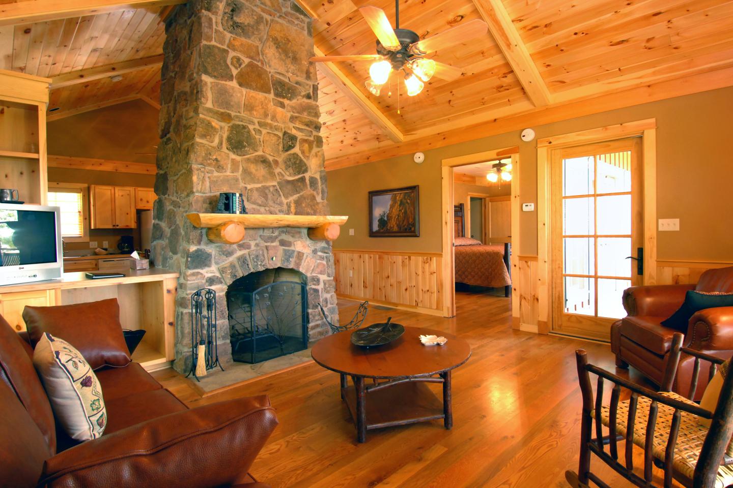Warm, cozy living room with stone fireplace, leather sofas, and wooden interior.