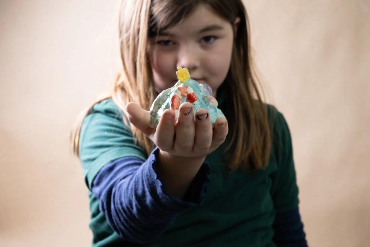 Young girl holding a small figurine towards the camera.