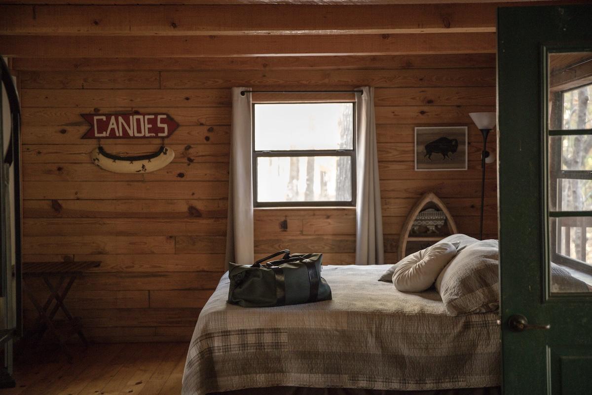 Cozy wooden bedroom with a bed, a window, and canoe decor.