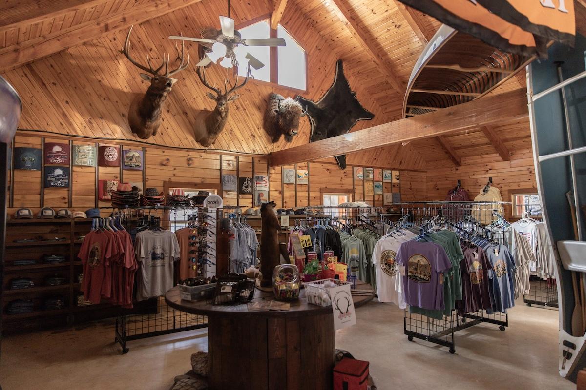 Cozy wooden shop interior with clothes on racks and mounted animal heads on walls.