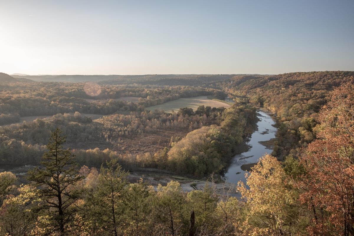 River winding through a forested valley under a clear sky at sunset.