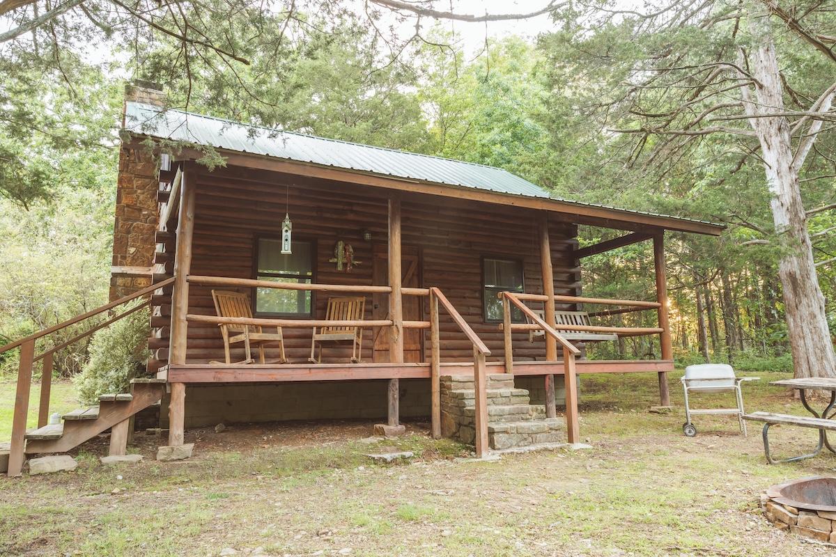 Cozy wooden cabin with porch in a forest setting.
