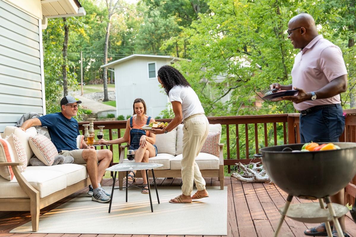 Group enjoying a barbecue on a deck, surrounded by trees.