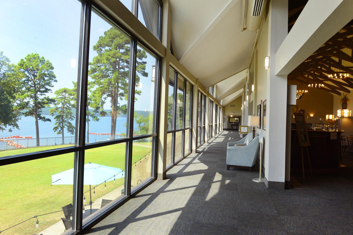 Long glass hallway overlooking a lake with trees.