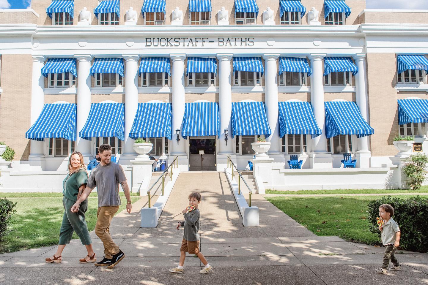 Family walking in front of a building with blue striped awnings.