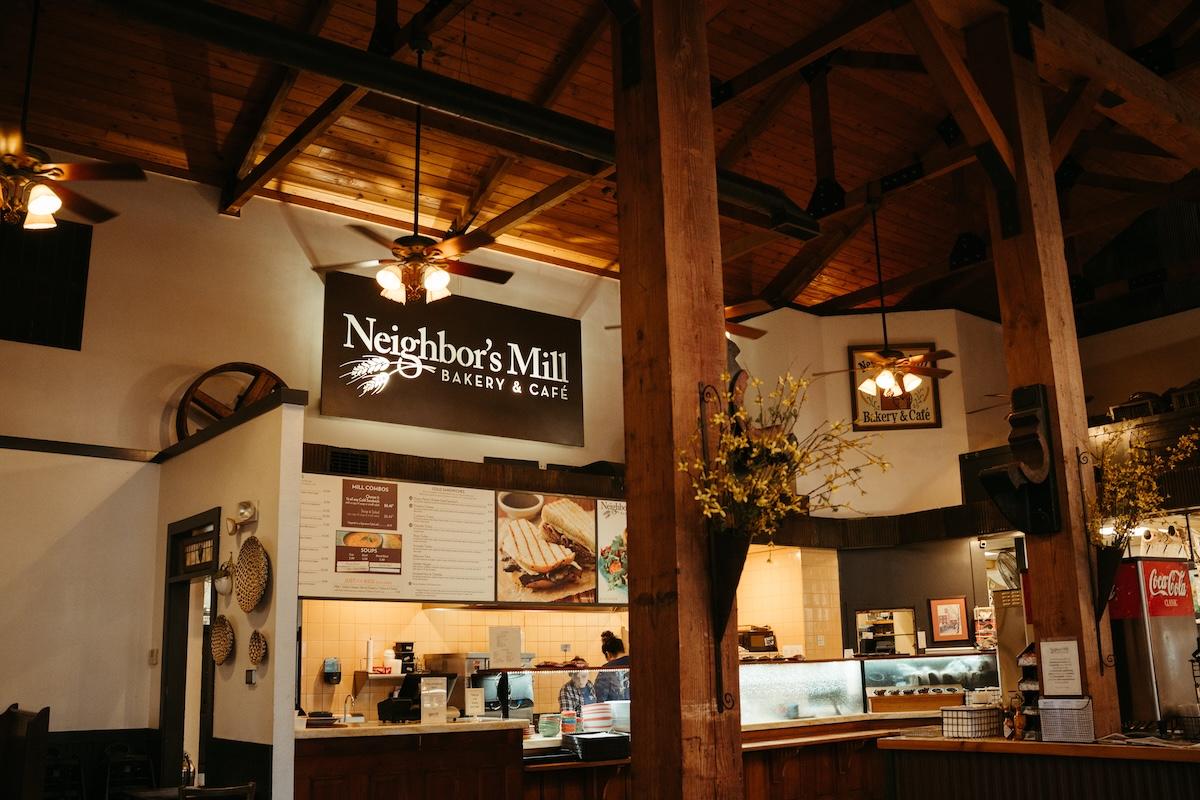 Rustic café interior with wooden beams and a counter displaying food.