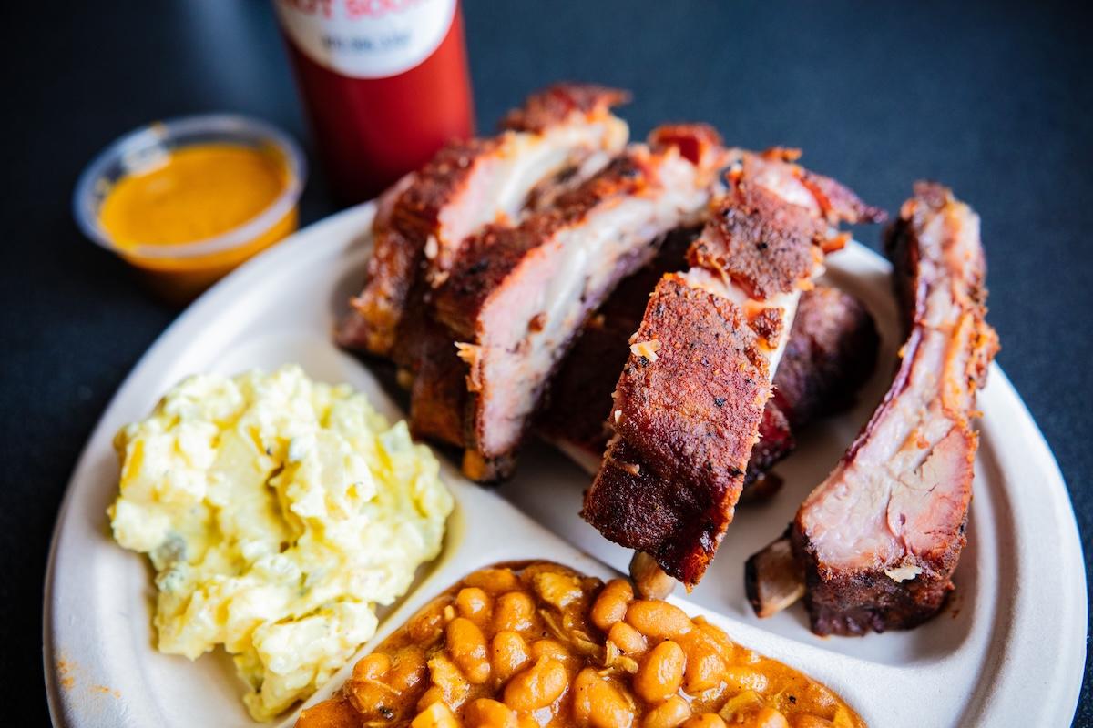 Barbecue ribs with mashed potatoes and beans on a plate.