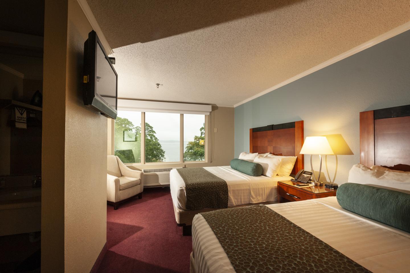 Hotel room with two beds, a window view, and a lamp-lit nightstand.