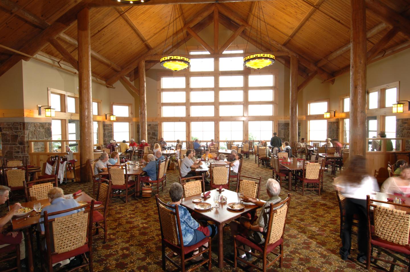 Large dining hall with high wooden ceilings, filled with people at tables.