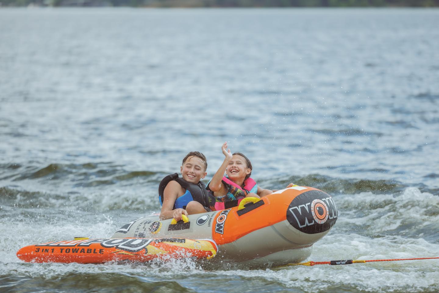 Two people smiling on an inflatable boat on a lake.