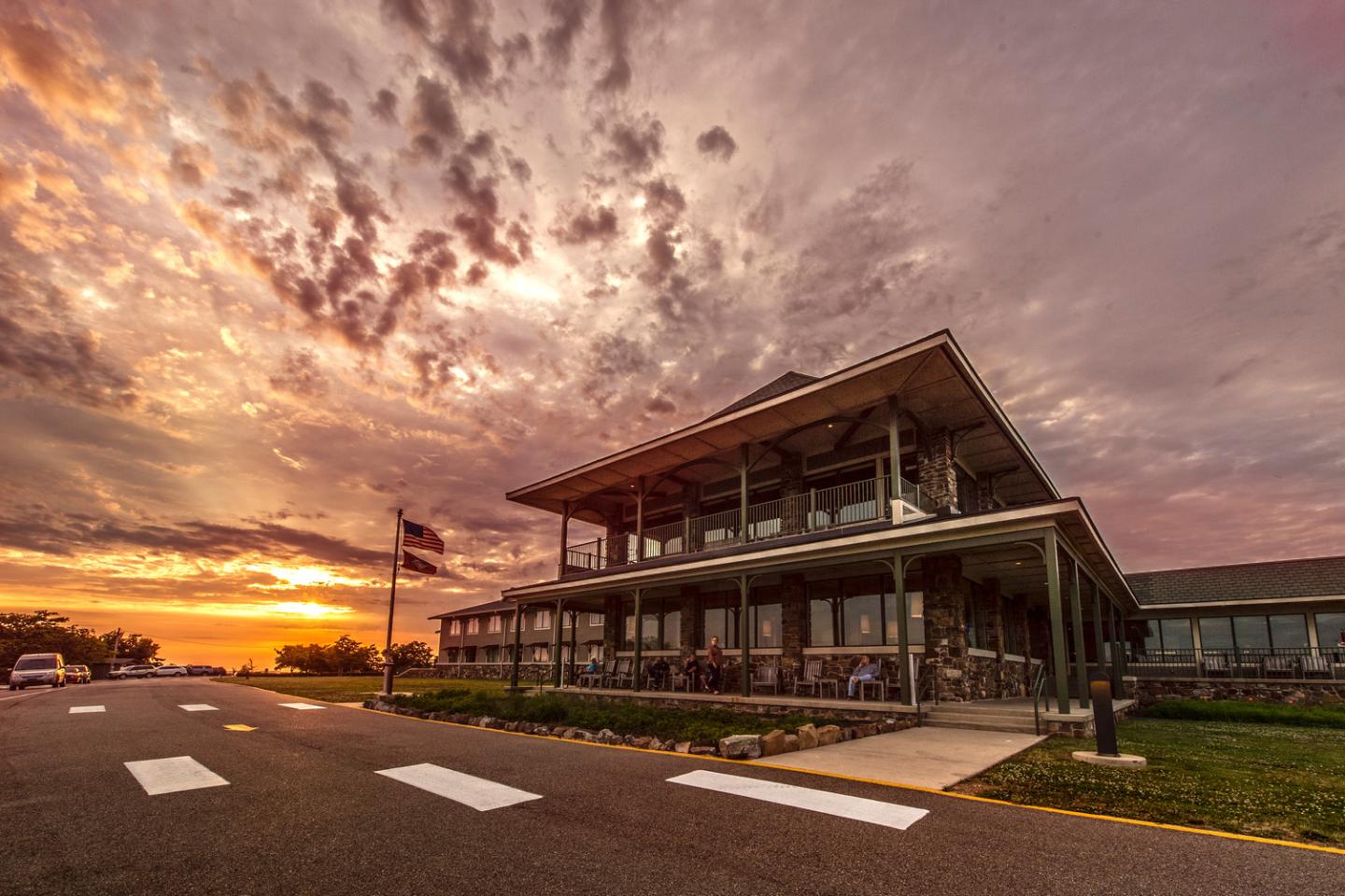 Sunset over a large, two-story building with dramatic clouds.