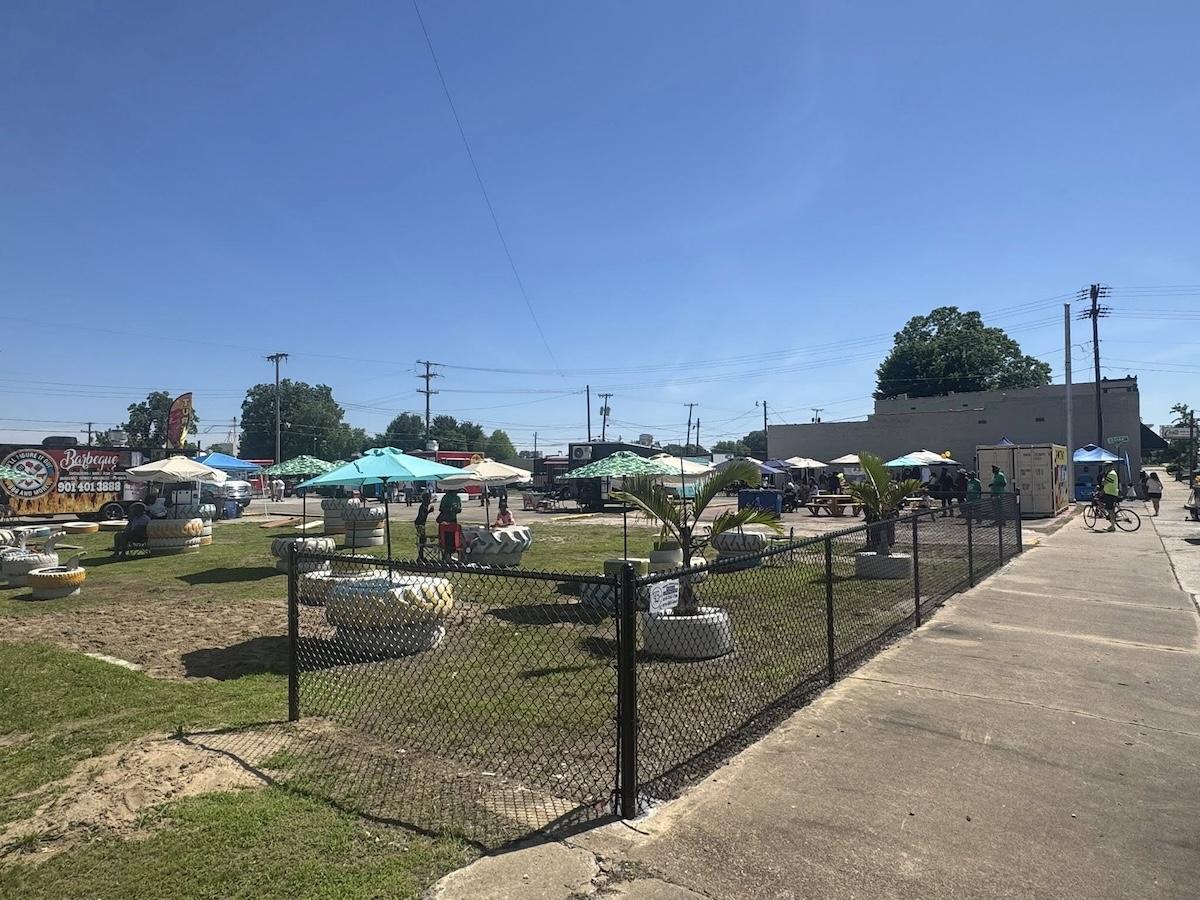 Outdoor market with tents and umbrellas on a sunny day.
