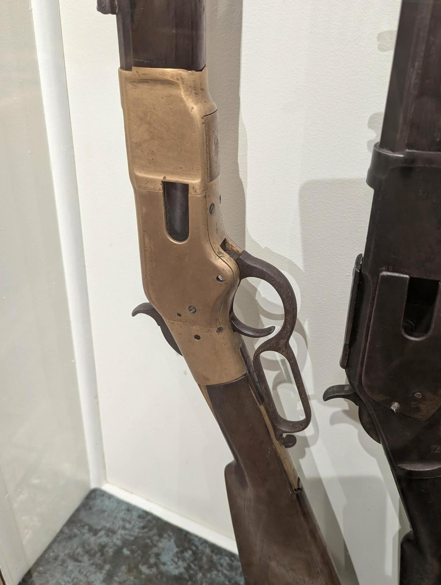 Lever-action rifle with wooden stock and brass receiver displayed upright.