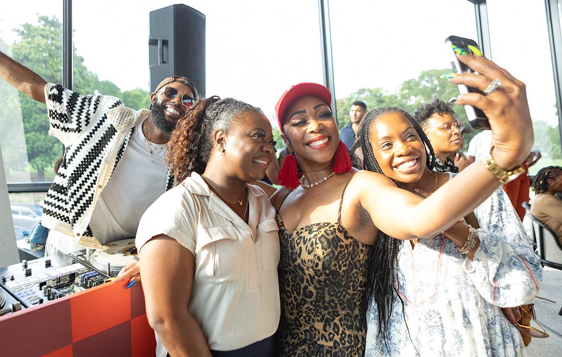 Women smiling and taking a selfie at a lively indoor event.
