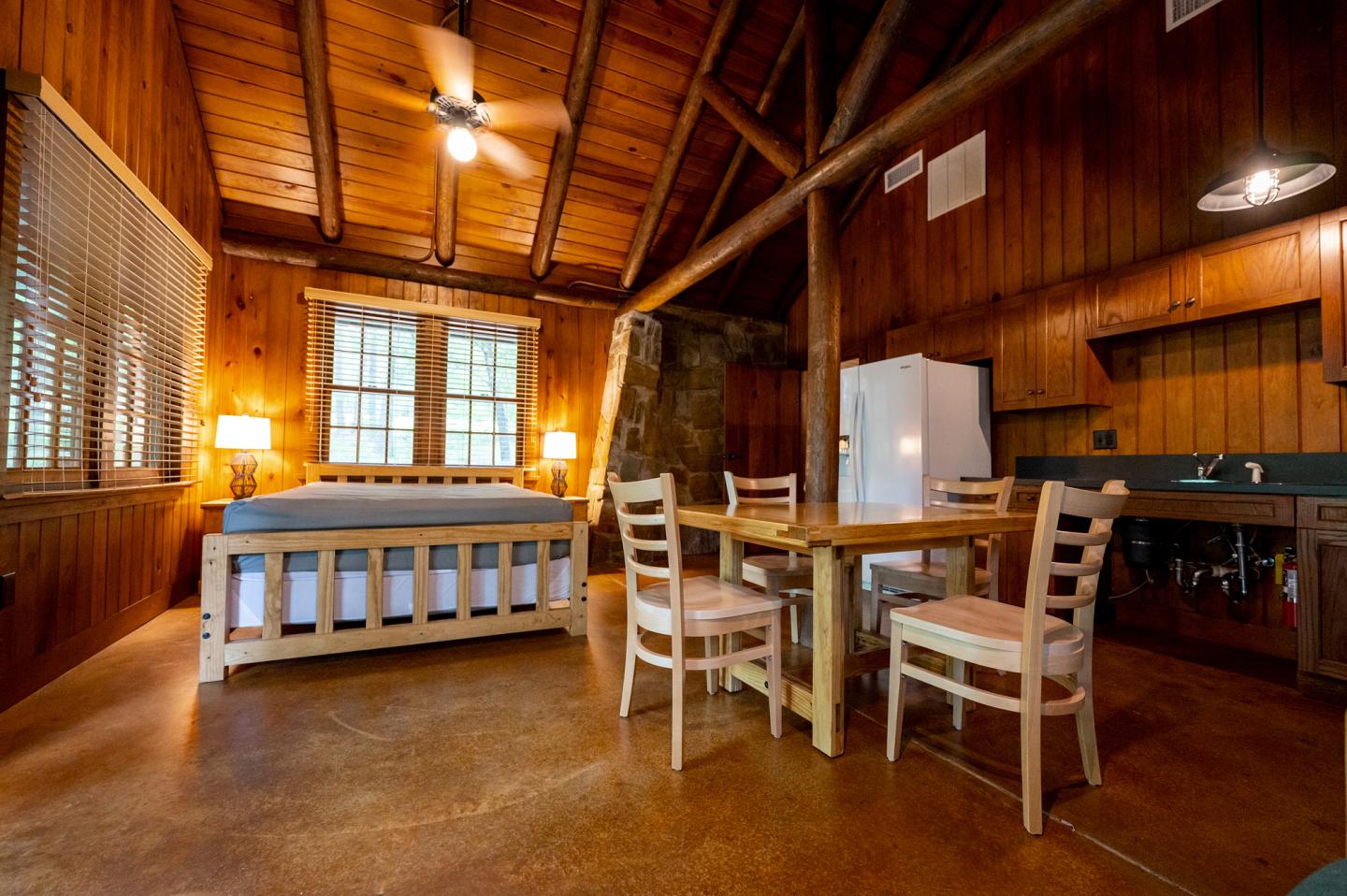 Cozy wooden cabin interior with bed and dining table.