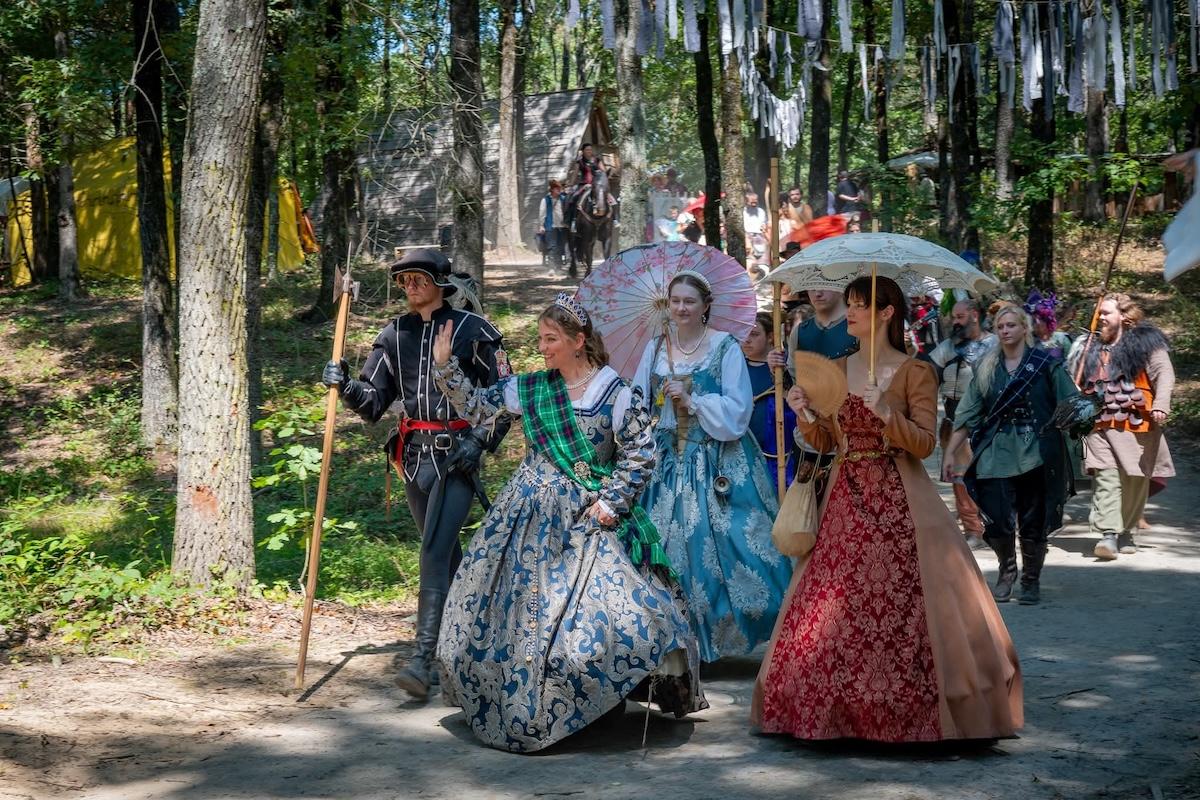 Group in historical costumes walking in a wooded area.