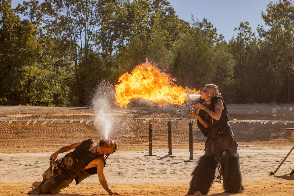 Fire performers in an outdoor setting, one breathing fire, the other water.