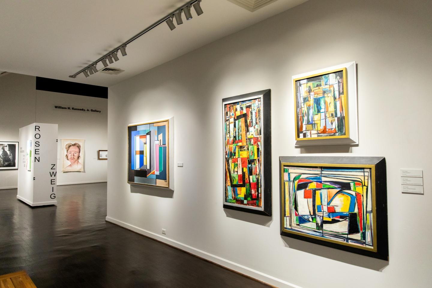 Modern art gallery with colorful abstract paintings on white walls.