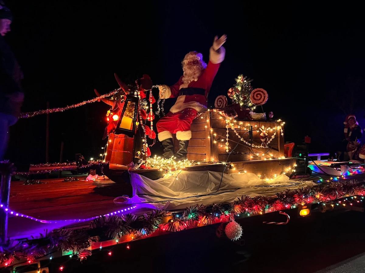 Santa on a lit parade float at night.