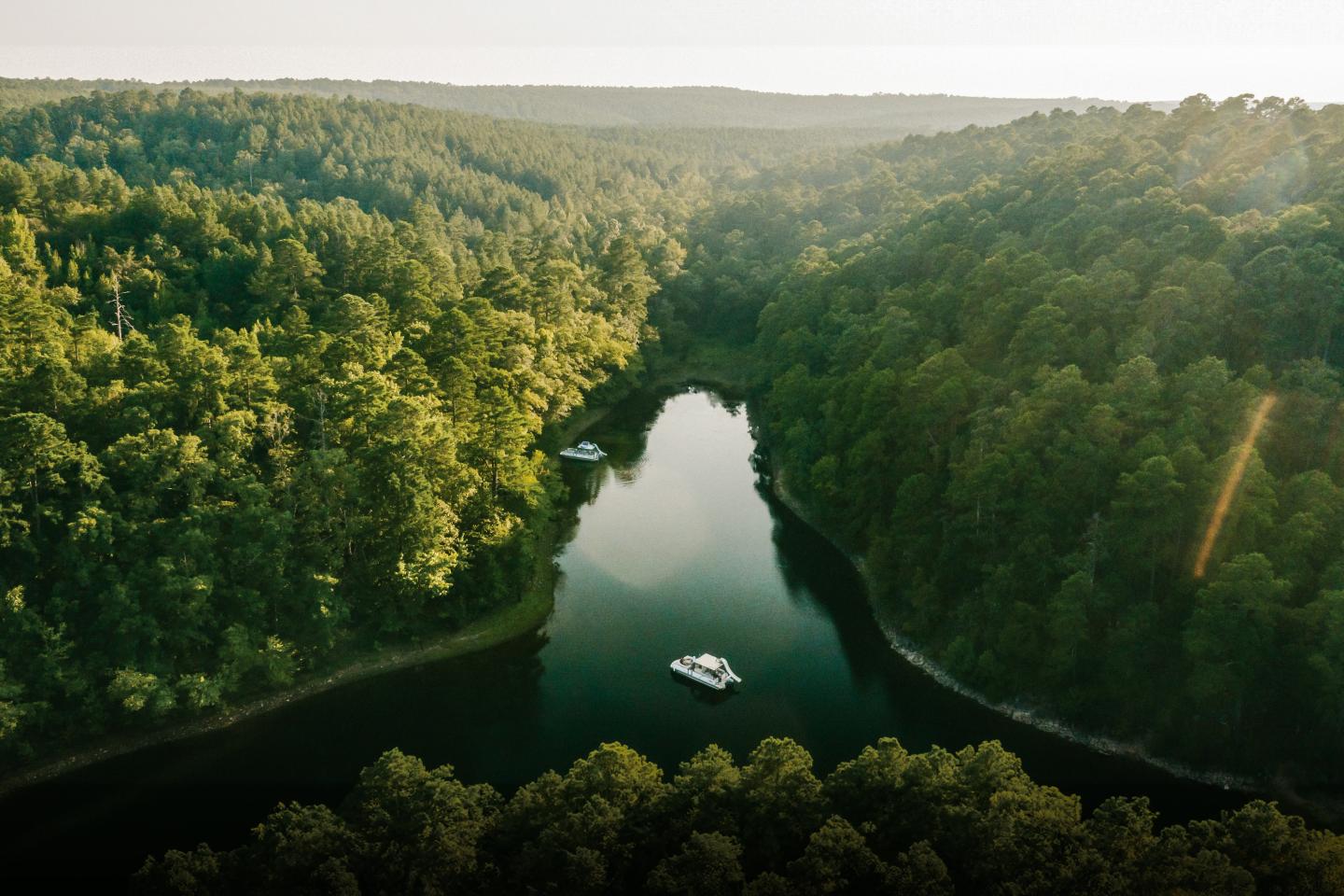 Forest-surrounded lake with a small boat in the center.