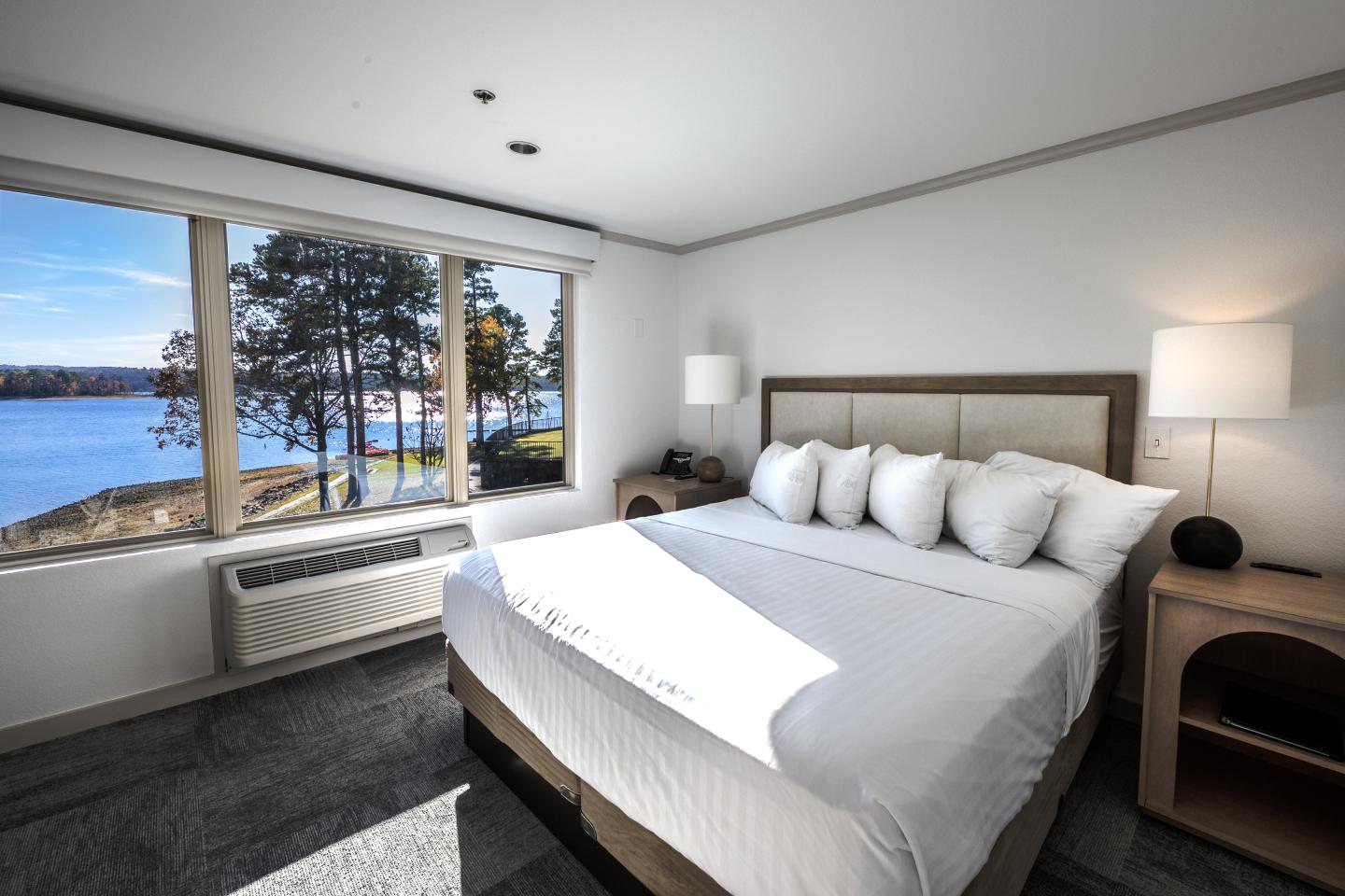 Bright hotel room with a lake view, king bed, and modern decor.