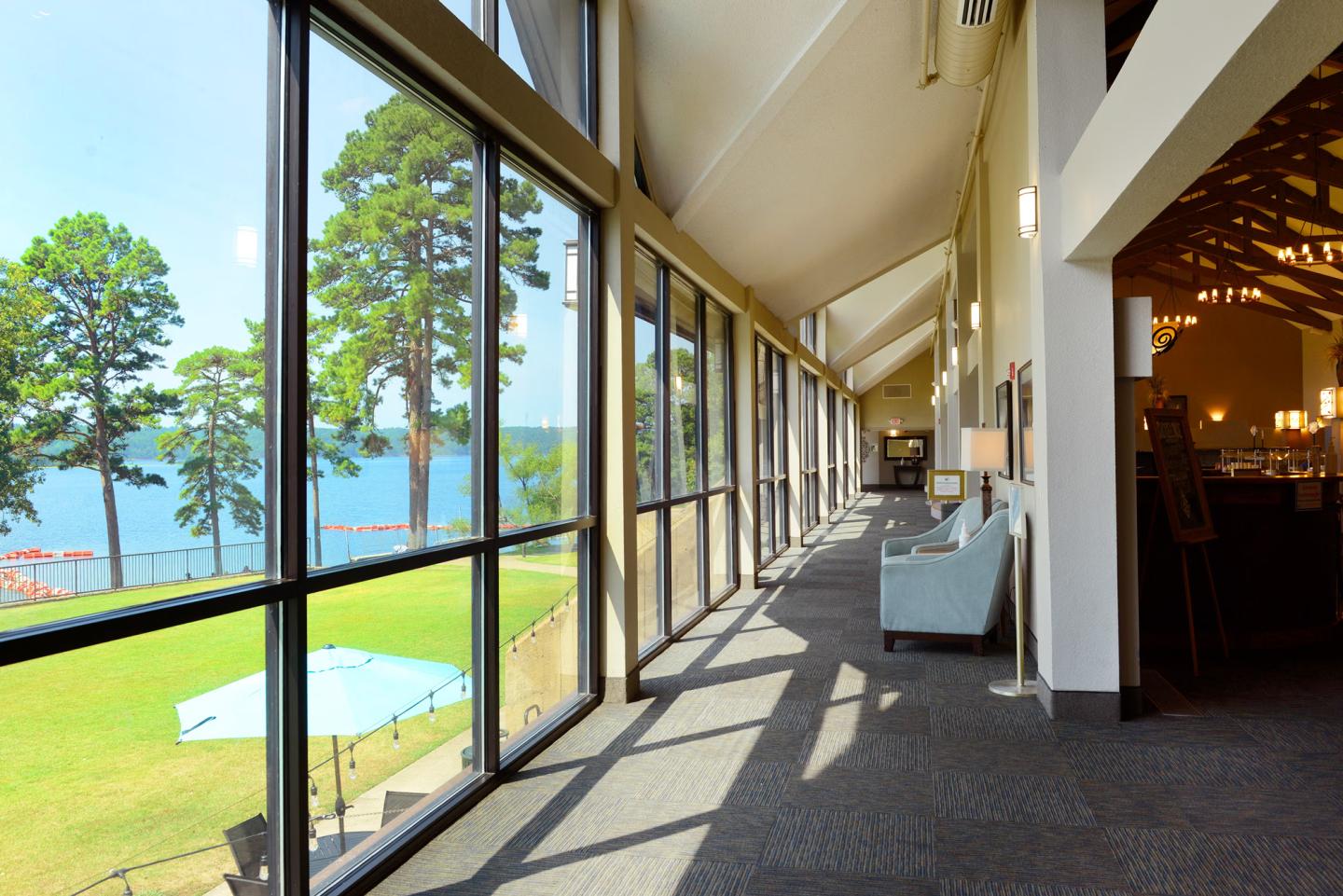 Spacious room with large windows overlooking a lakeside view and lush trees.