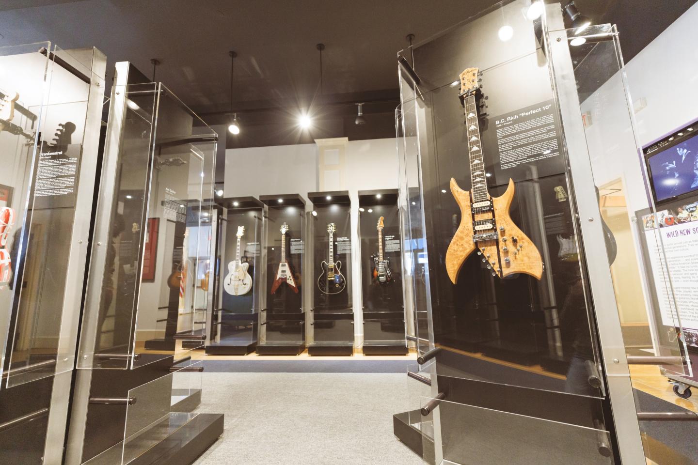 Guitar exhibit in a museum with guitars in glass cases.