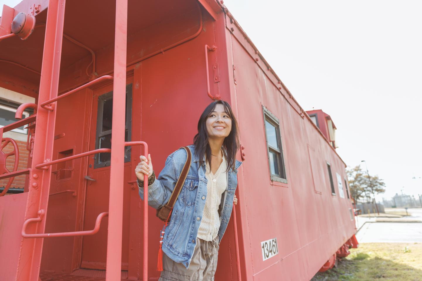 Smiling person standing at the entrance of a red train cabin.