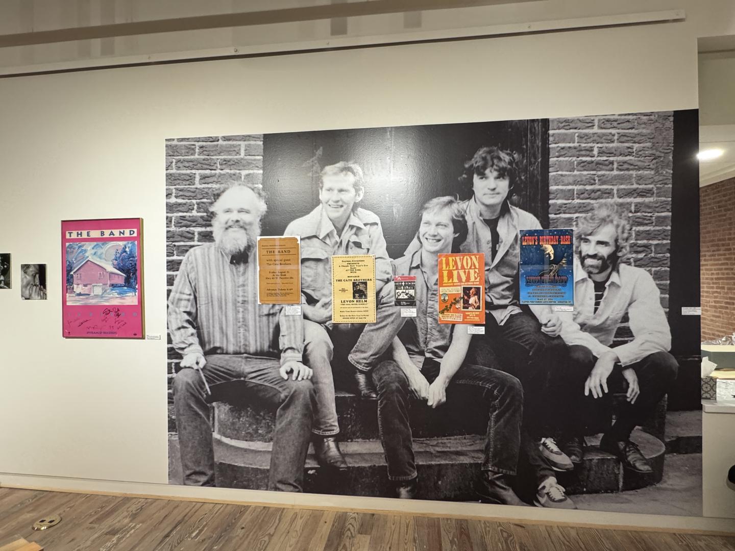 Black and white photo of six people with colorful posters on a wall.