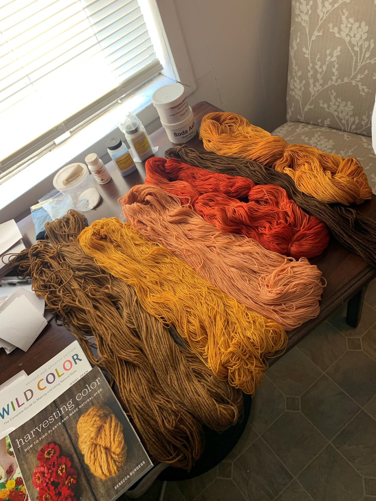 Colorful yarn skeins on a table with a book.