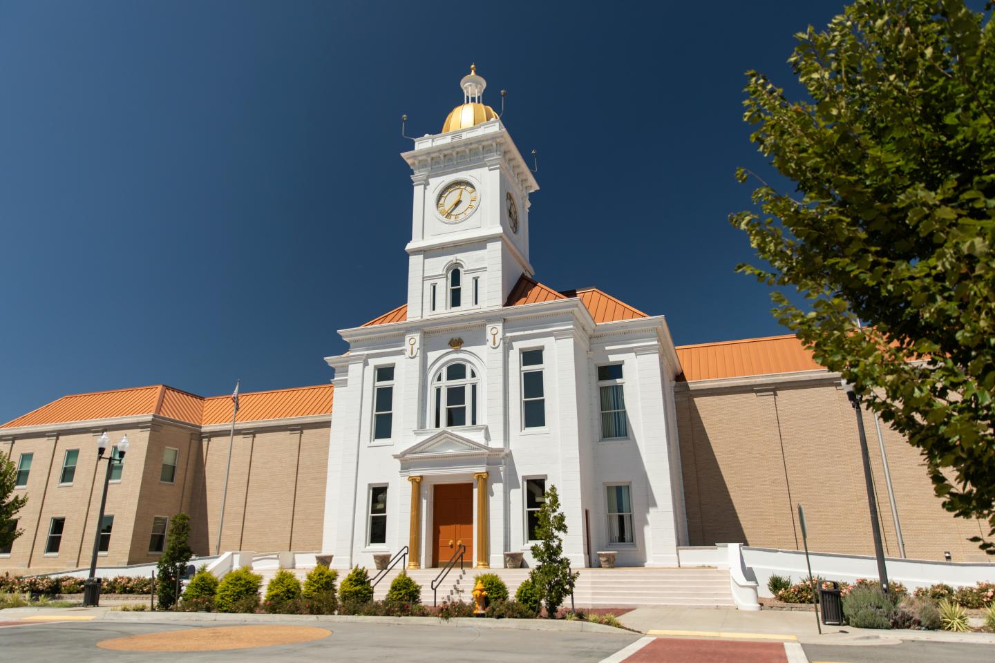 Elegant building with clock tower, red roof, clear blue sky.
