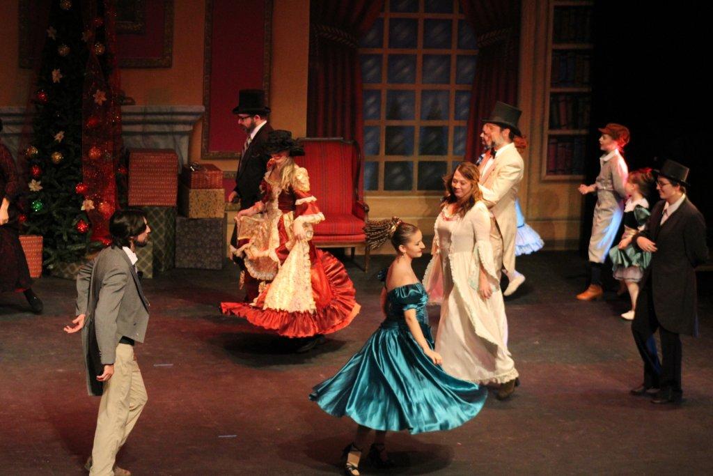Victorian-era dancers in colorful costumes performing on stage.