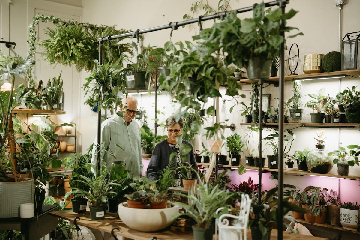 Two people in a lush plant store with various potted plants.