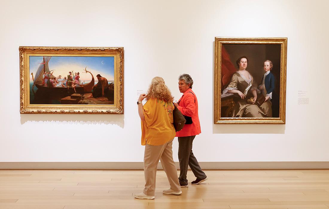 Two women viewing paintings in a museum gallery.