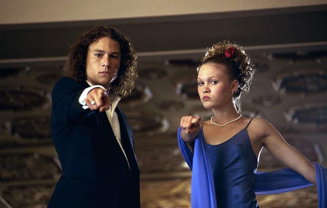 Young couple in formal attire, looking serious, indoors with ornate ceiling.